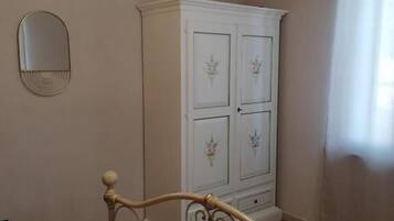Une chambre à coucher comprenant un lit, une armoire, un miroir et un luminaire suspendu.
