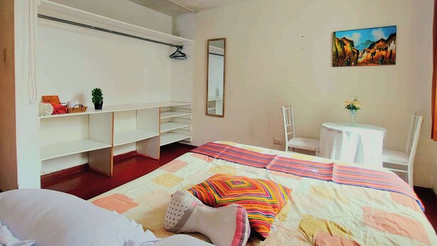 A bedroom with a bed, a desk, a chair, a mirror, and a painting on the wall. - Sumaq Wasi Inca Trails (Lima)