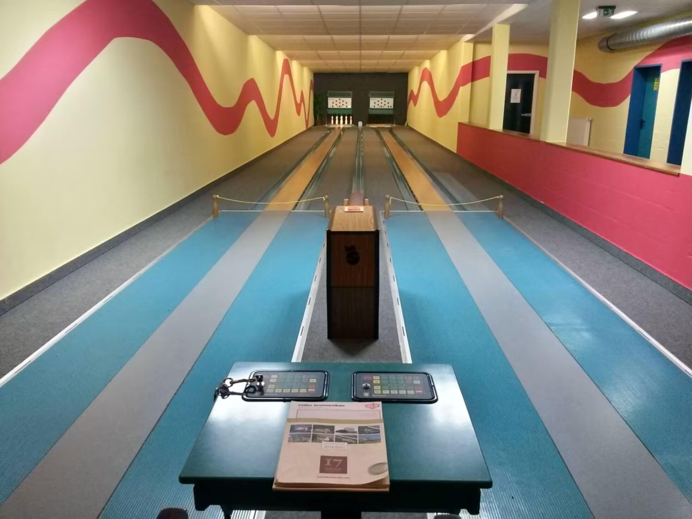 Una pista da bowling con piste di gioco, un lanciapin e un tabellone dei punteggi.