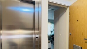 An elevator with a digital display, a wooden door, and a carpeted floor. - Modern Apartment in Myyrmäki – Direct Train to Helsinki & Airport (Vantaa)
