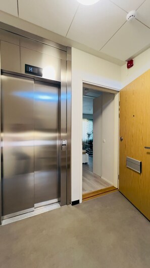 An elevator with a digital display, a wooden door, and a carpeted floor.