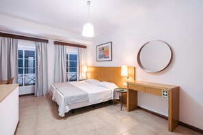 Ein Hotelzimmer mit Bett, Nachttisch, Lampe und Blick auf die Stadt durch das Fenster.