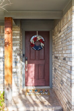 A wooden door with a wreath, a mailbox, and a doormat with boots and the word 'HOWDY'.