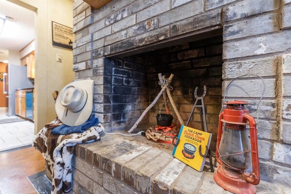 A brick fireplace with a book titled 'The Camp Dutch Oven Cookbook' and a red lantern.