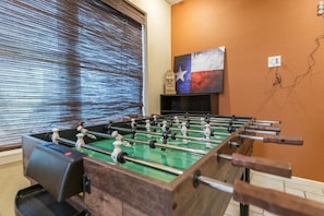 A foosball table in a room with a Texas flag decoration and a wall socket. - Waffle House | Pool · Game Room · Putting Green · (Abilene)