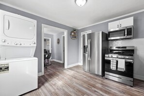 Una cocina moderna con refrigerador de acero inoxidable, microondas, horno y lavavajillas integrado.