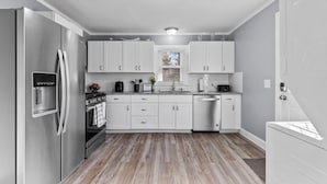 A modern kitchen with stainless steel appliances, white cabinetry, and a wooden floor. - Cozy Getaway Near Downtown Concord (Concord)