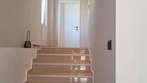 A staircase leading to a door with a light fixture on the wall. - Te bunkeri (Ersekë)