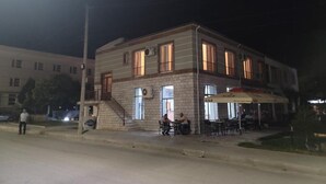 A two-story building with a ground-level cafe area and a staircase leading to the upper floor. - Te bunkeri (Ersekë)