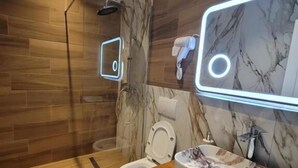 A modern bathroom with a wooden floor, a marble vanity, a toilet, and a shower. - Te bunkeri (Ersekë)