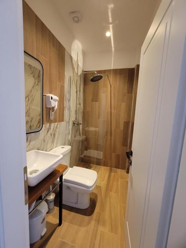 A modern bathroom with a marble sink, a toilet, and a shower area. - Te bunkeri (Ersekë)