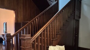 Una escalera de madera con barandilla, un banco e iluminación en la pared.
