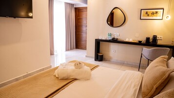 A hotel room with a bed, a desk, a chair, a mirror, and a TV.