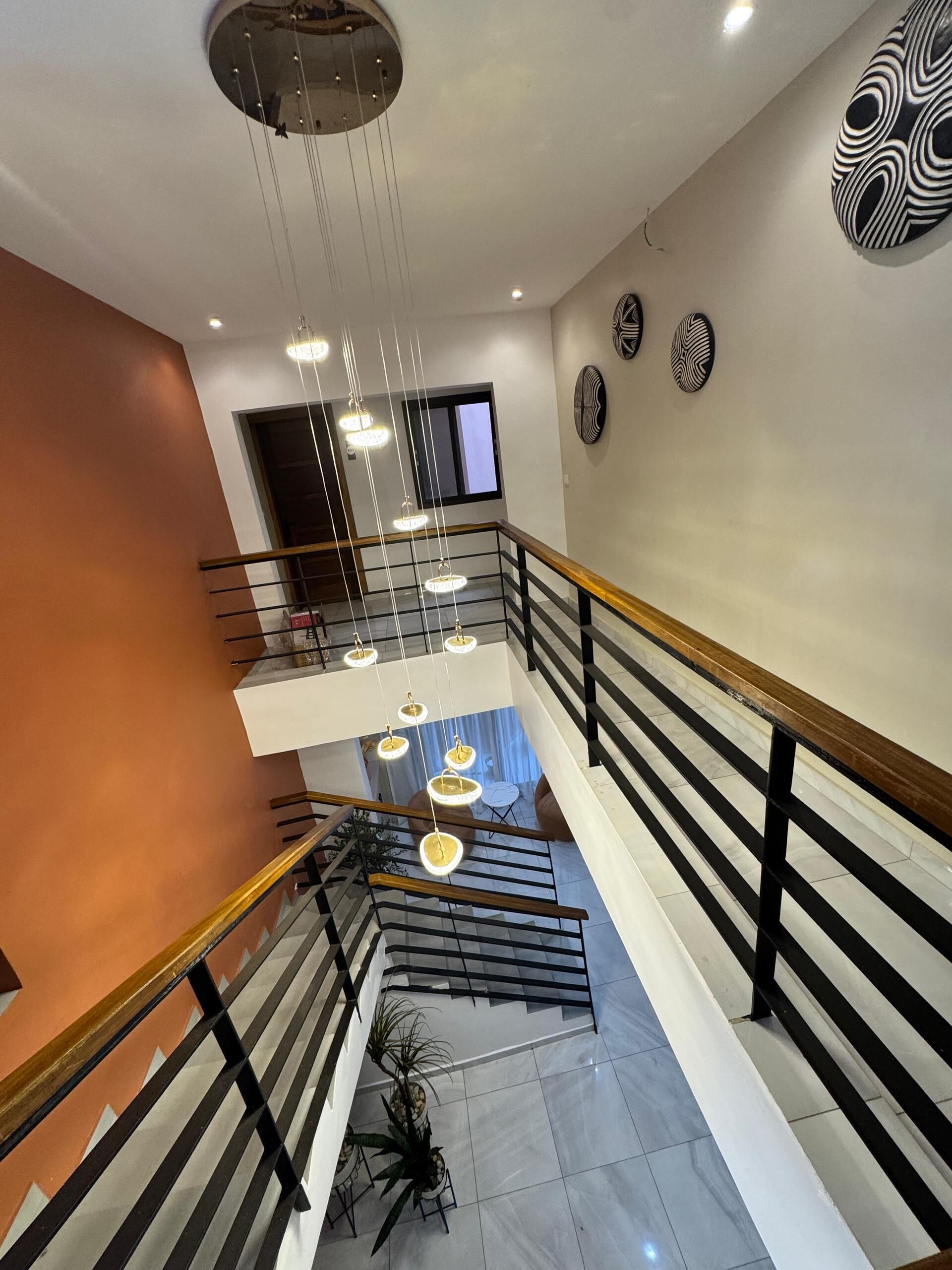 A multi-level interior with a staircase, pendant lights, and decorative wall art.