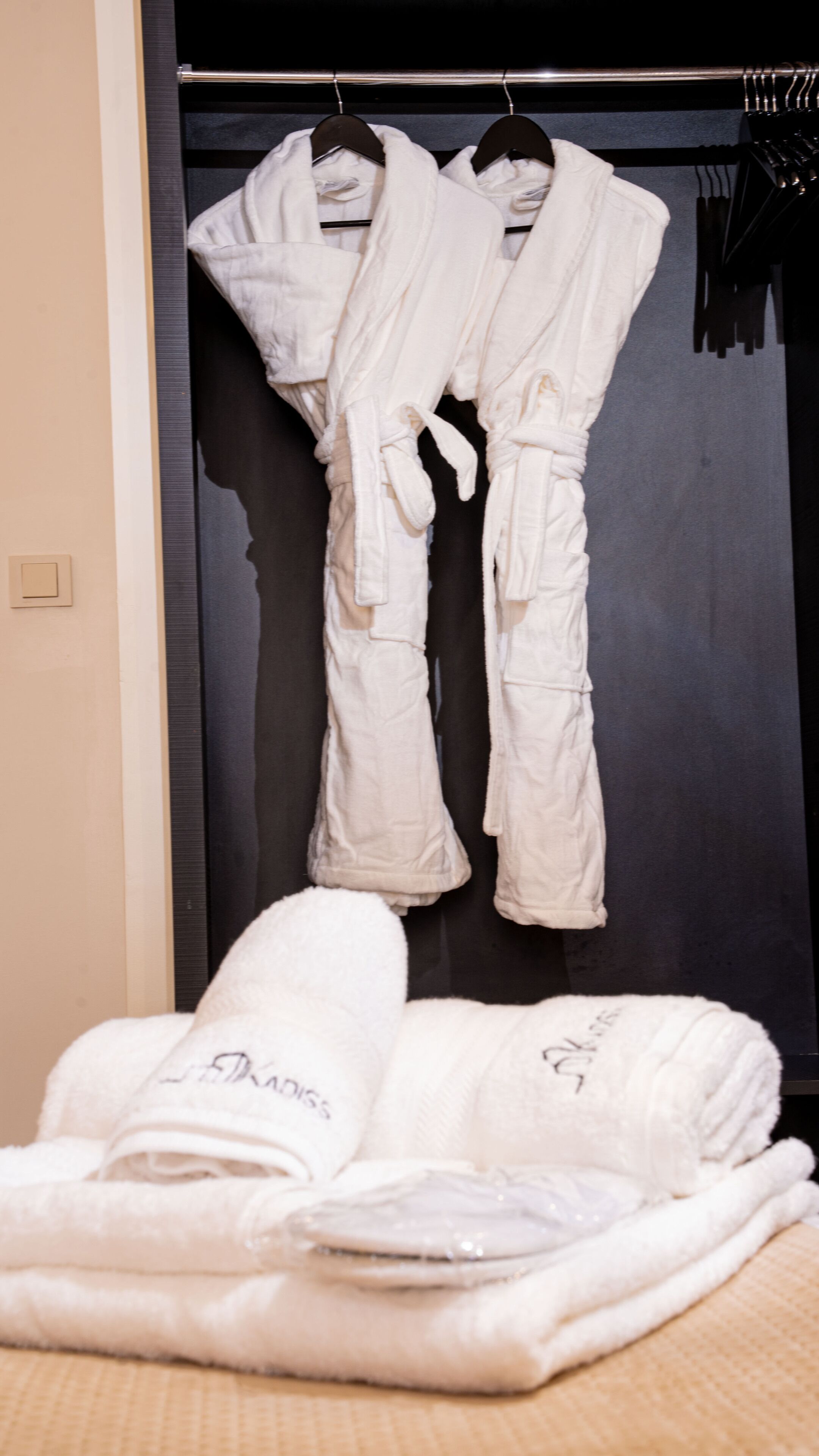 Une chambre d’hôtel avec un placard contenant des peignoirs et des serviettes blancs.