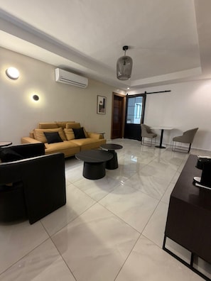 A modern living room with a sofa, two round tables, a coffee table, and a TV.