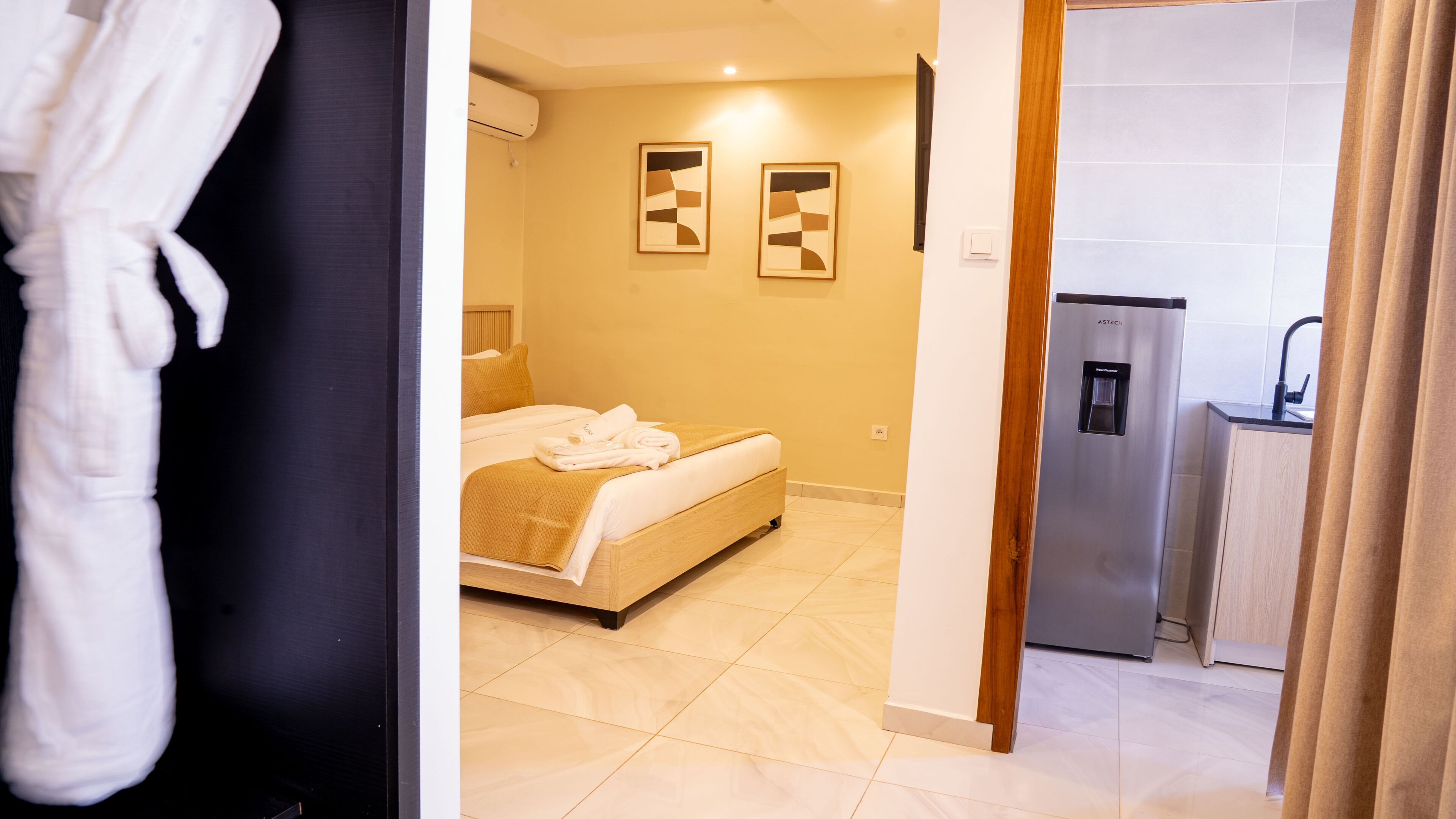 Habitación de hotel con cama, dispensador de agua y zona de ducha.