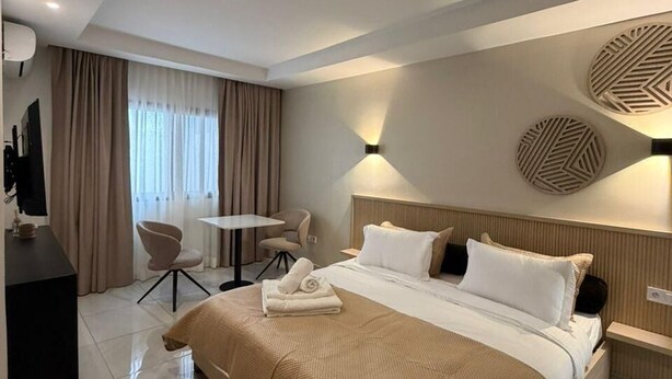 A modern hotel room with a large bed, a desk, a chair, and a television. - Kadiss Hotel (Dakar)