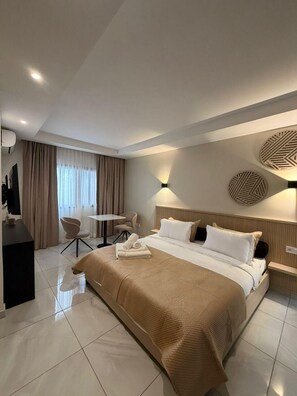 A modern hotel room with a large bed, a desk, a chair, and a television. - Kadiss Hotel (Dakar)