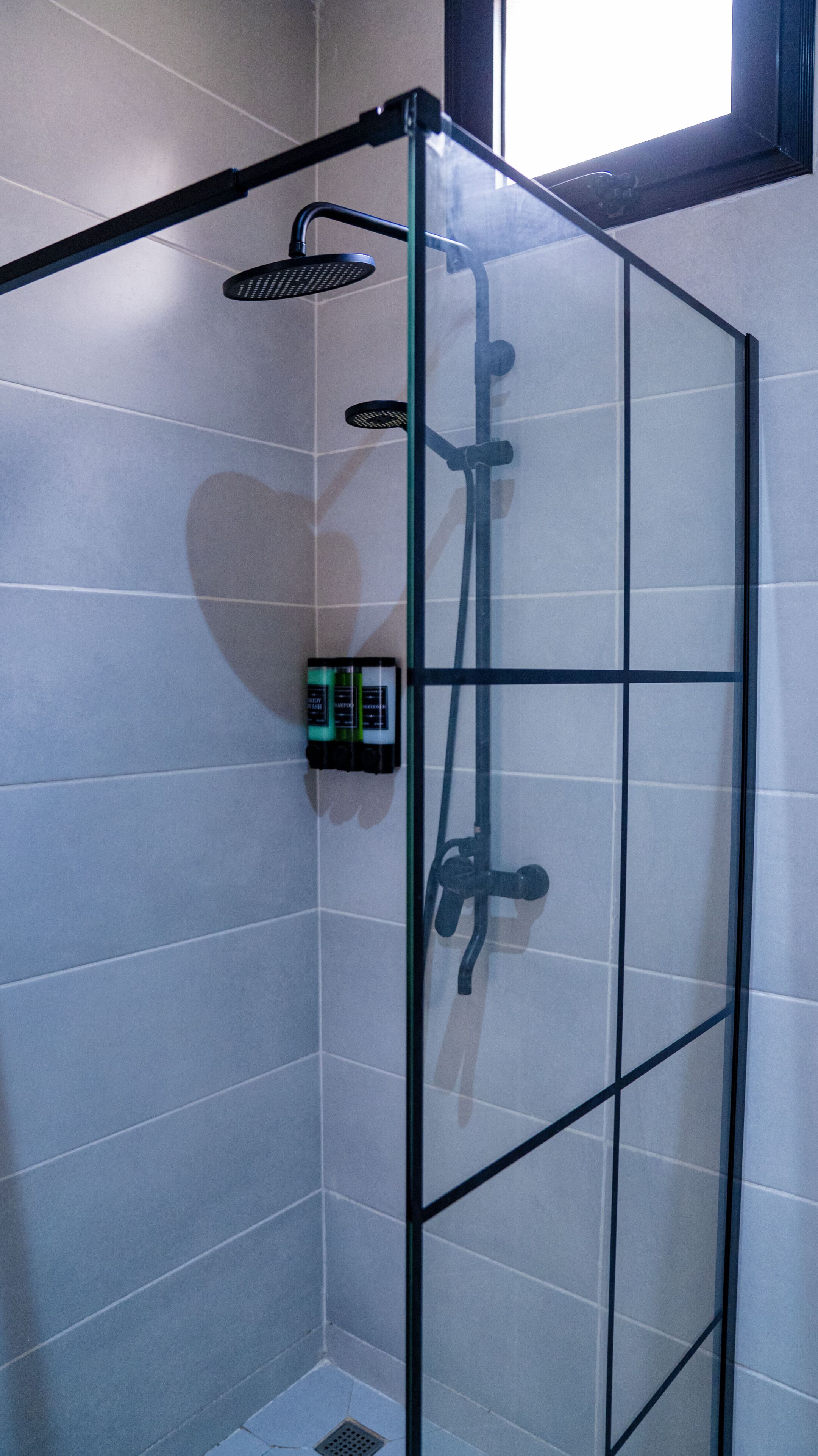 A shower enclosure with a control panel, a handheld showerhead, and a wall-mounted showerhead.