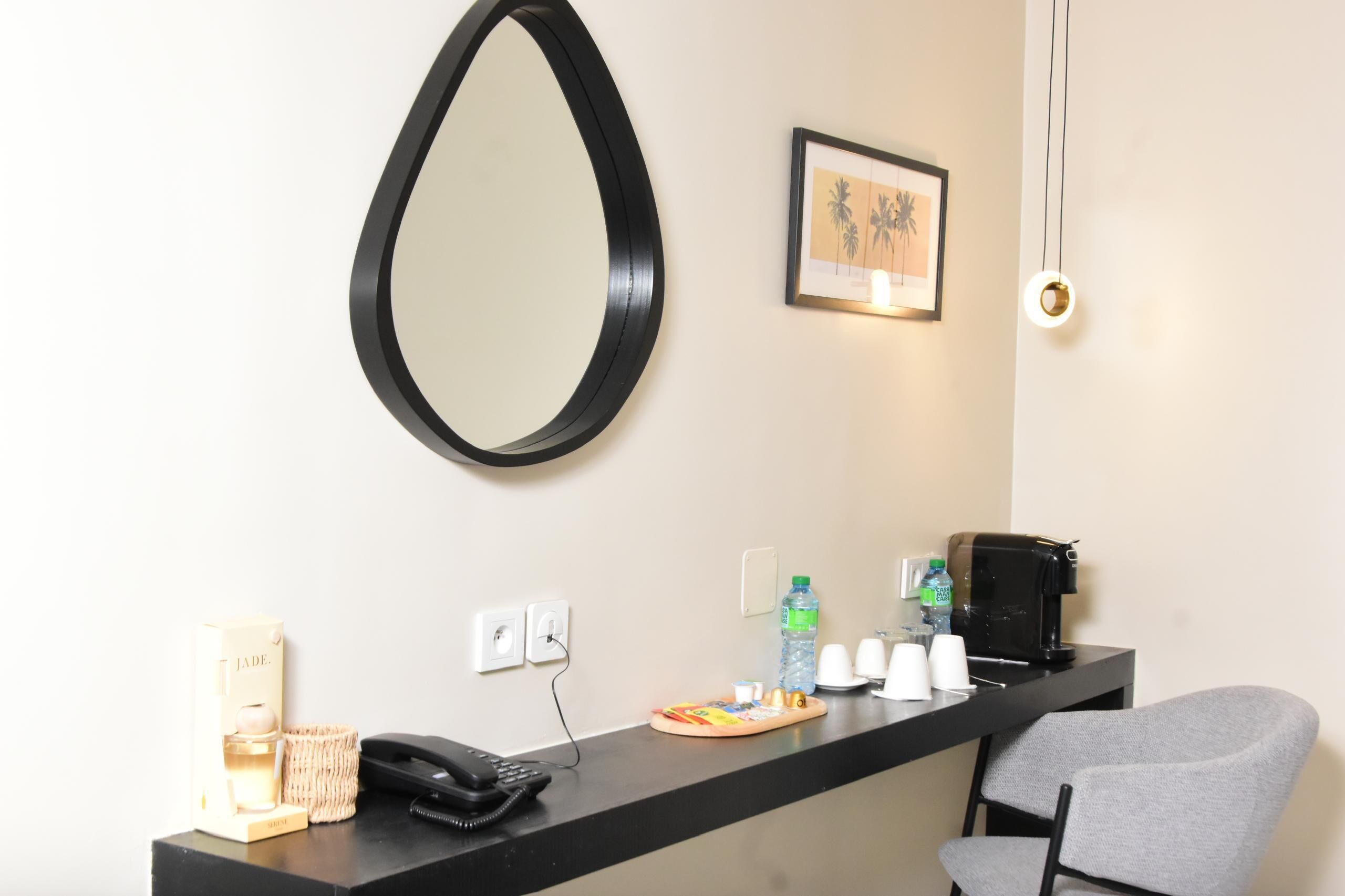 A reception desk with a telephone, coffee maker, water bottle, cups, and a framed picture on the wall.