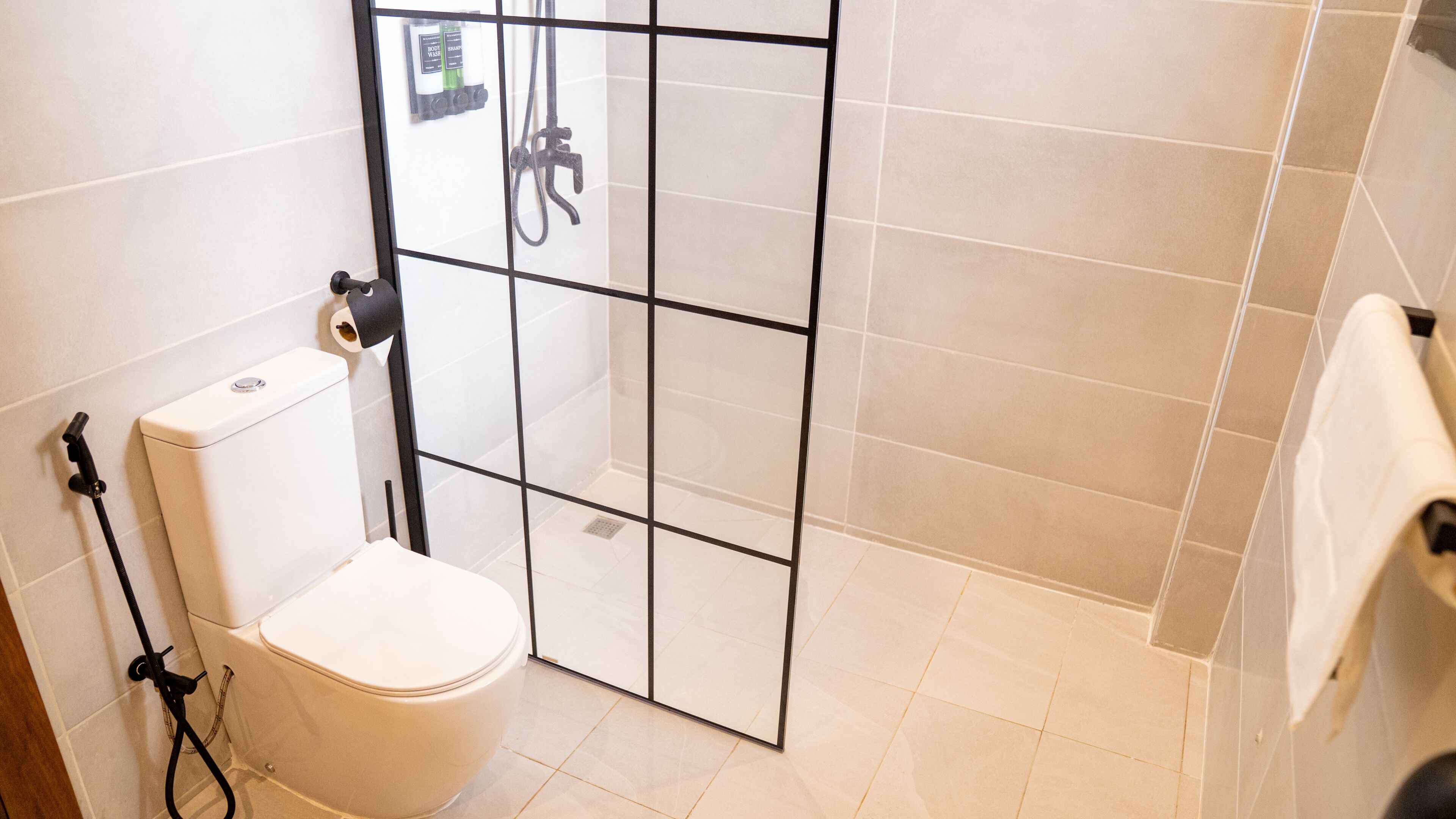 A bathroom with a toilet, a shower area, and a towel rack.