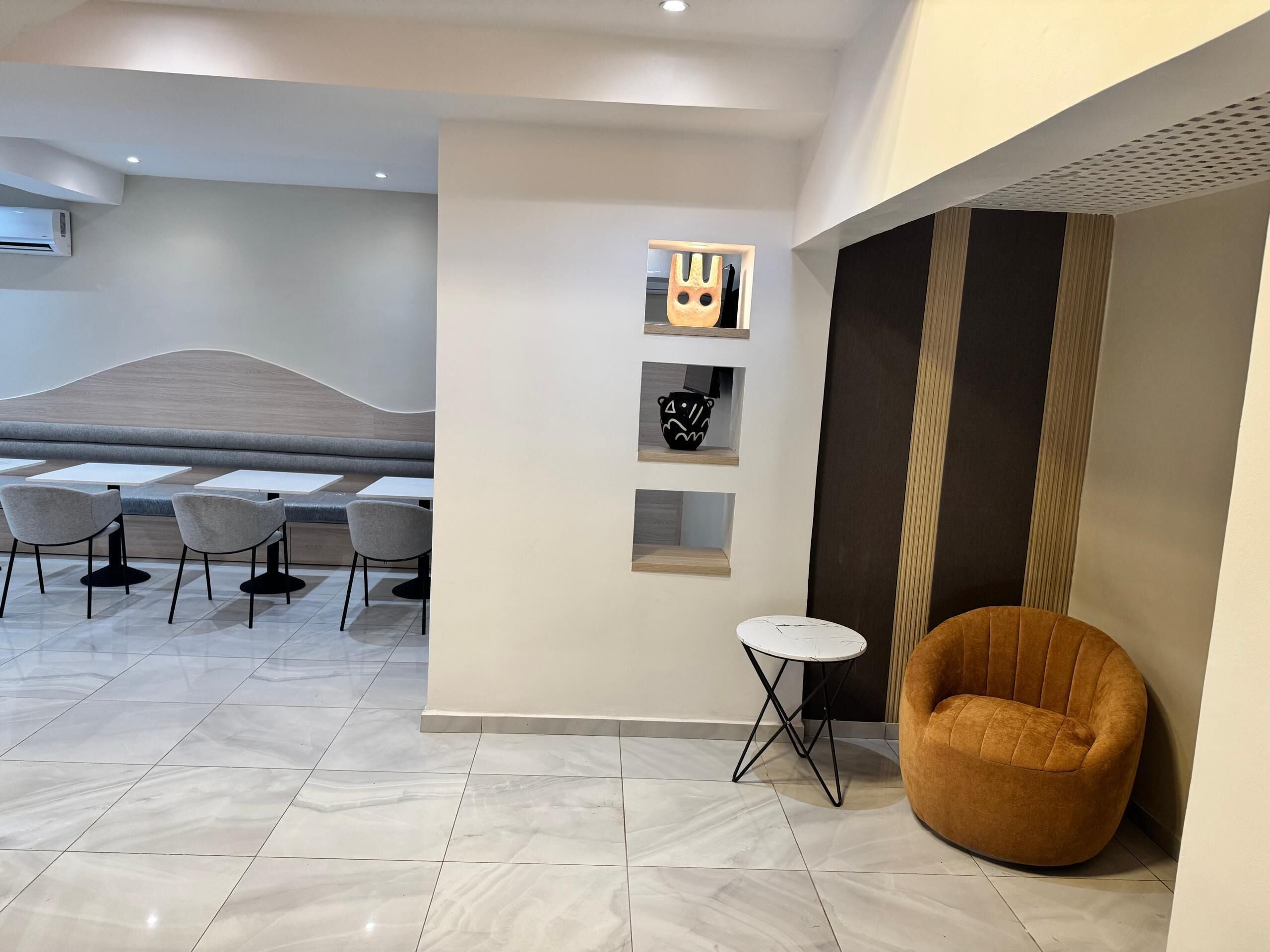 A modern interior with a seating area, a small table, and decorative shelves.