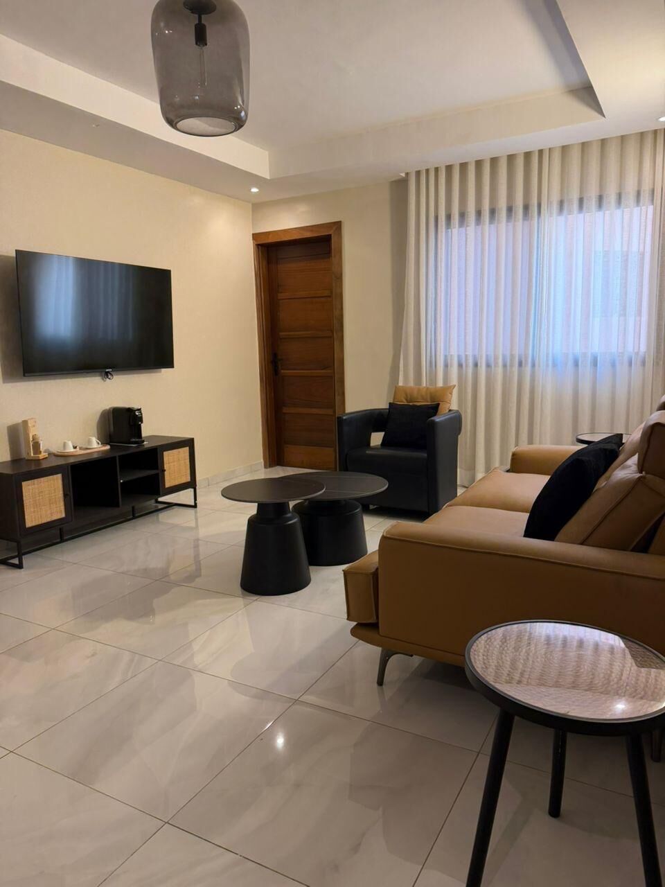 A modern living room with a flat-screen TV, a sofa, a coffee table, and a side table.