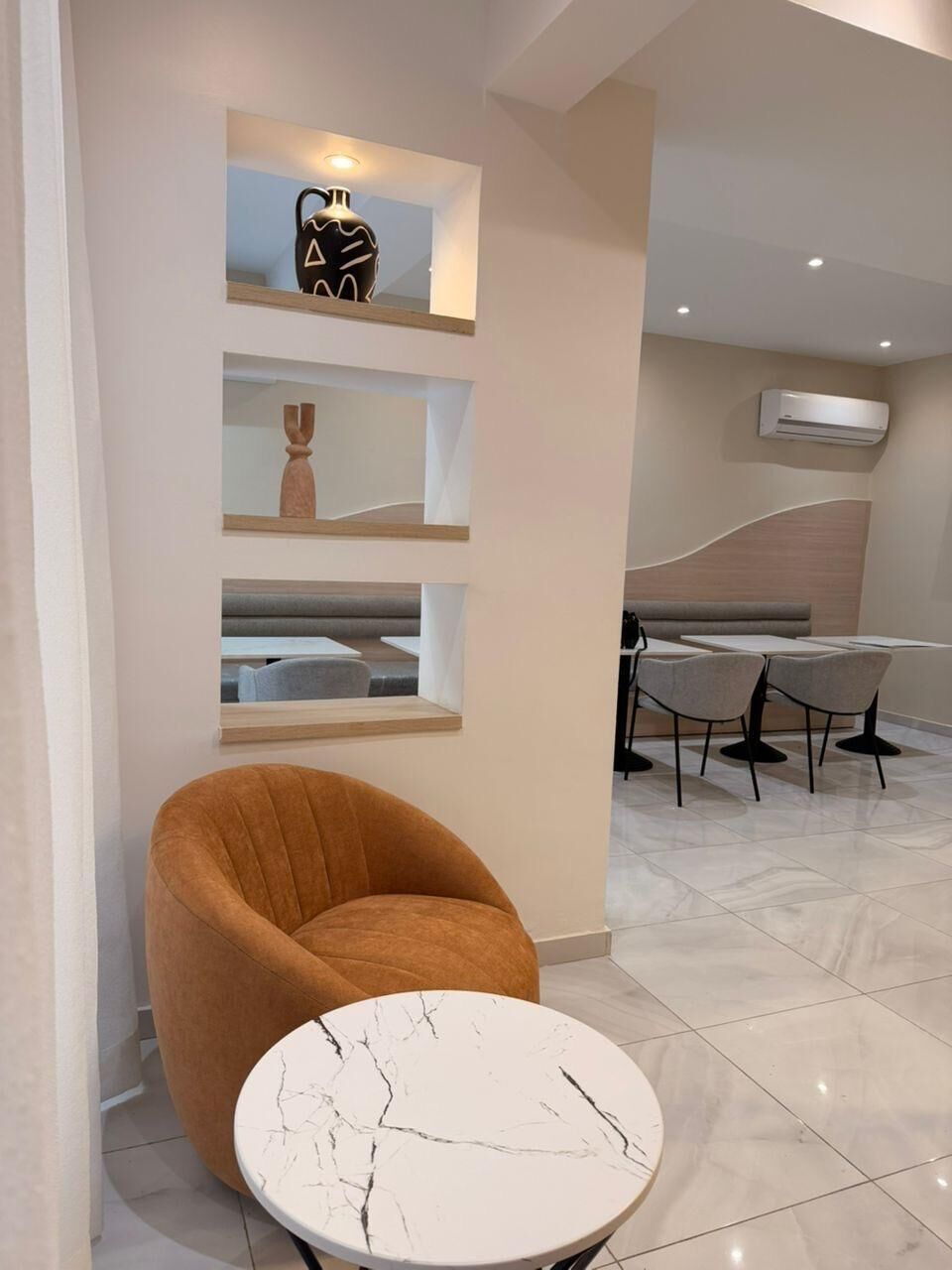 Un intérieur moderne avec une table ronde, un fauteuil confortable et un espace salon comprenant des tables et des chaises.