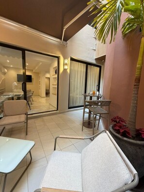 A hotel room with a balcony, a dining area, and a view of the interior.