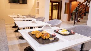 A dining area with tables, chairs, and a breakfast spread including croissants, eggs, and ham. - Kadiss Hotel (Dakar)