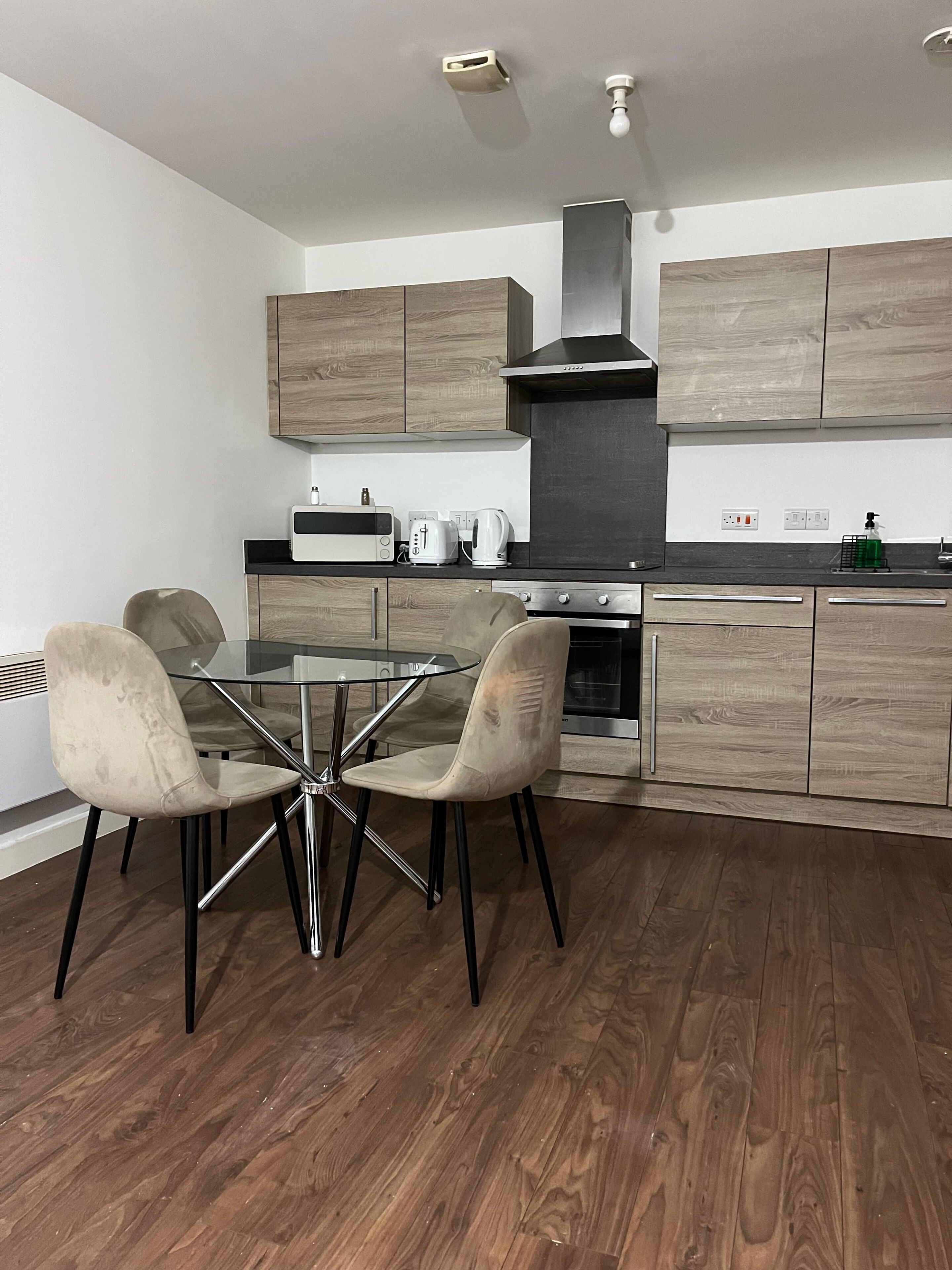 Una cucina moderna con mobili in legno, un tavolo da pranzo in vetro e un piano cottura in acciaio inossidabile.
