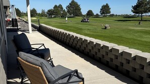 Eine überdachte Terrasse mit Korbstühlen und einer Betonwand.
