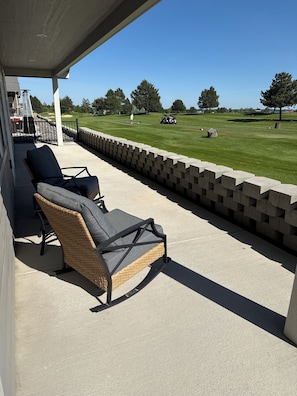 A covered patio with wicker chairs and a concrete wall.