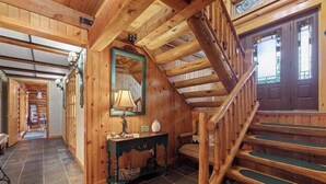 Ein Holzinterieur mit Treppe, Spiegel und einem Tisch mit Lampe.