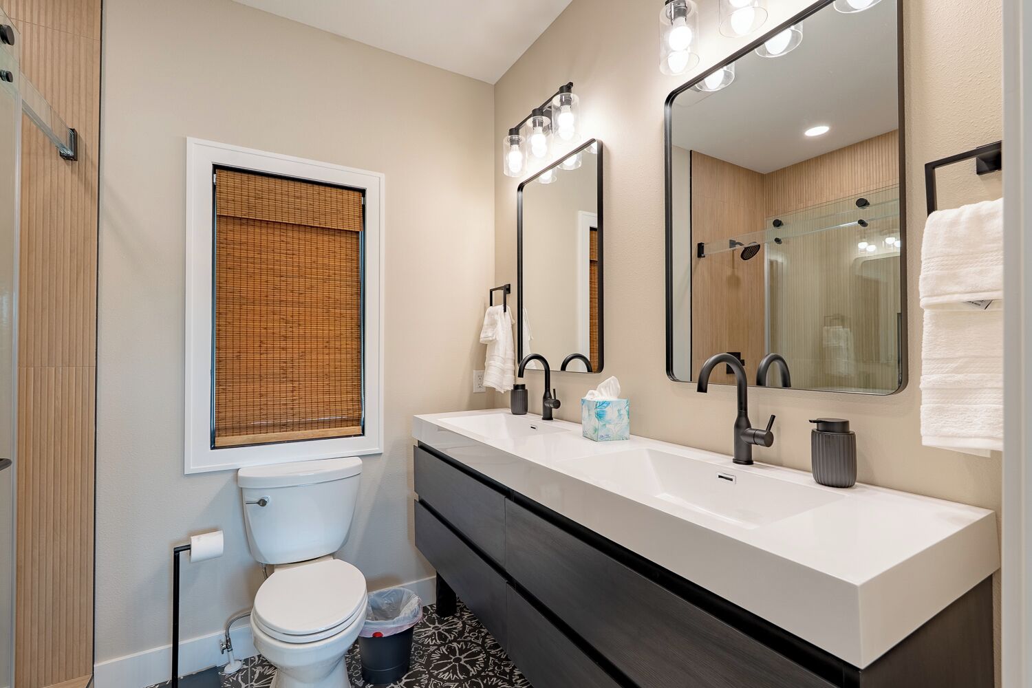 A modern bathroom with a toilet, bidet, two sinks, and large mirrors.