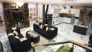 A spacious living area with a black sofa set, a coffee table, and a dining table with green plates.