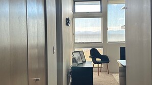 Käytävä, jossa on työpöytä, tuoli ja suuret ikkunat.