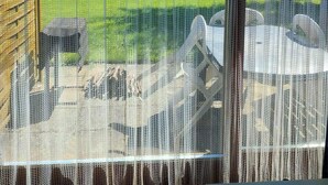 A view through a window with a mesh screen, a wooden fence, a grassy yard, and outdoor furniture. - 4 Star Holiday Home in Nykobing Sj (Nykobing Sjaelland)