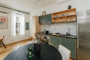 A modern kitchen with green cabinets, a Bosch refrigerator, and a dining area with a black table and chairs. - European Style Luxe 1BD, Walk to All OTR (Cincinnati)