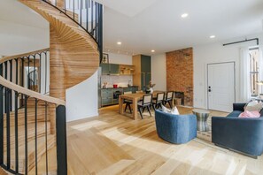 Un intérieur moderne avec un escalier en colimaçon, un coin repas et un espace de vie agrémenté d’une cheminée.