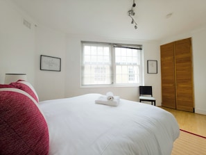 A bedroom with a large bed, a window with blinds, a wooden wardrobe, and a ceiling light fixture. - Stylish Flat Near Whitechapel - Pass the Keys (London)