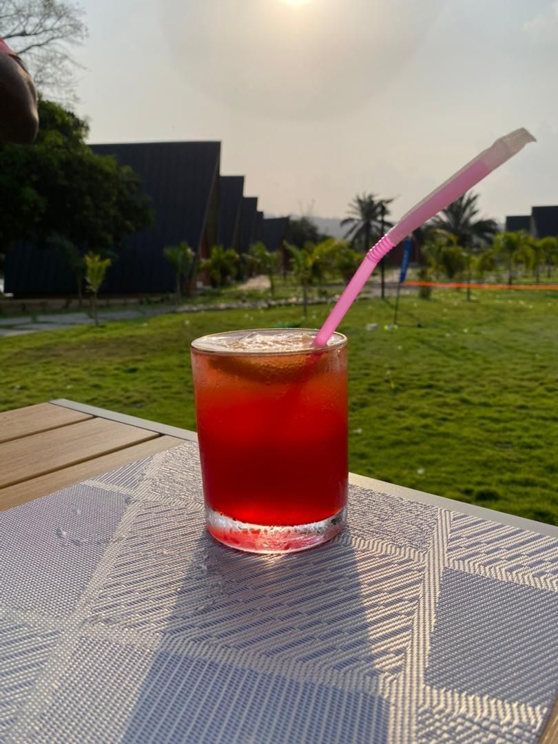 Un vaso de bebida roja con una pajita rosa sobre una mesa con un diseño geométrico.