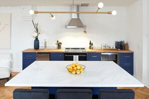 Een moderne keuken met een centraal eiland, een eettafel en een witte bakstenen muur.