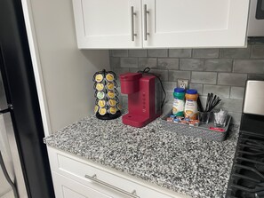 A kitchen counter with a coffee maker, a coffee creamer dispenser, and a coffee creamer bottle.