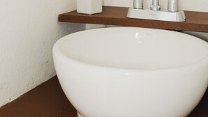 Un baño con un lavamanos blanco, un espejo y un dispensador de papel higiénico.