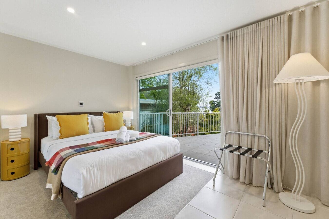 Una habitación de hotel moderna con una cama grande, un balcón y vistas al verdor.