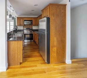 Una cucina moderna con mobili in legno, elettrodomestici in acciaio inossidabile e pavimento in legno.