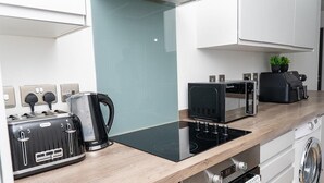 Een moderne keuken met een inbouwfornuis, broodrooster, waterkoker en magnetron.