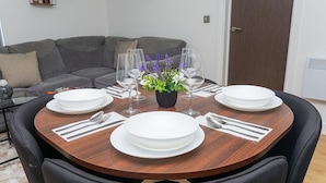 Een eettafel gedekt met borden, bestek en wijnglazen, omringd door stoelen.